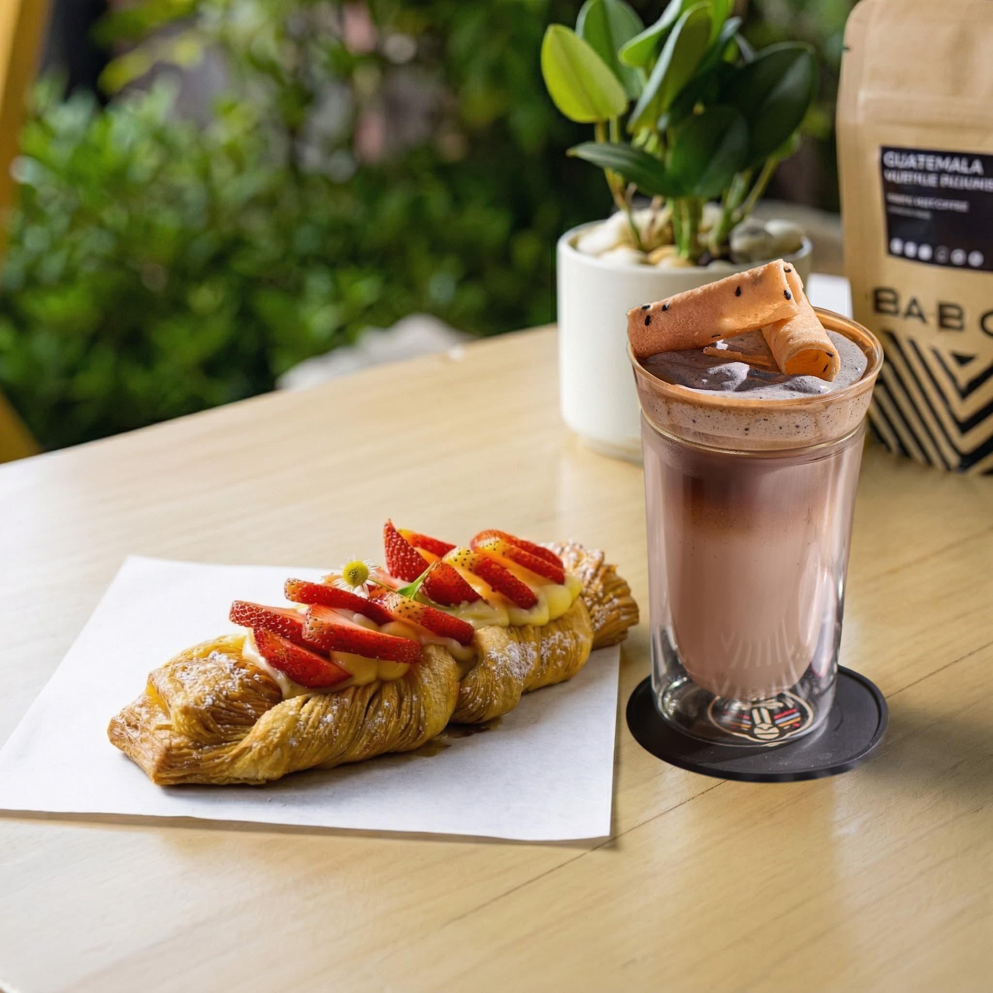 A croissant and signature drink on a sunlit table