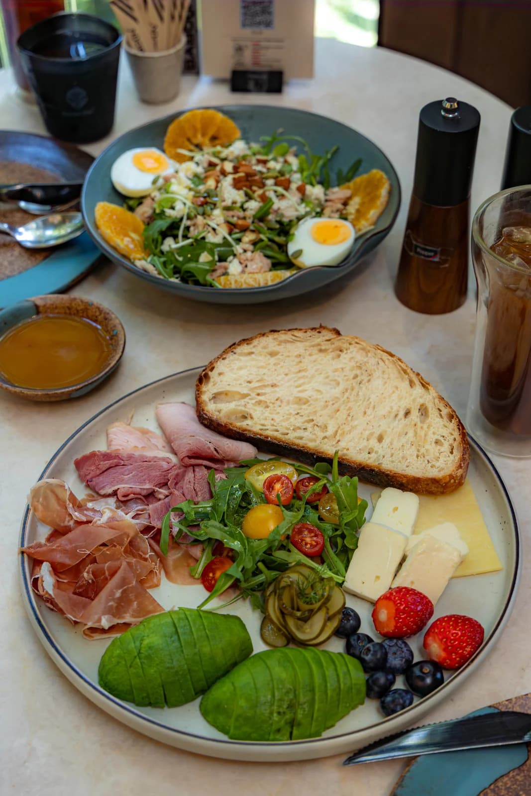 Breakfast plate with bread, cheeses, cured meats, avocado and fruit at Baboon