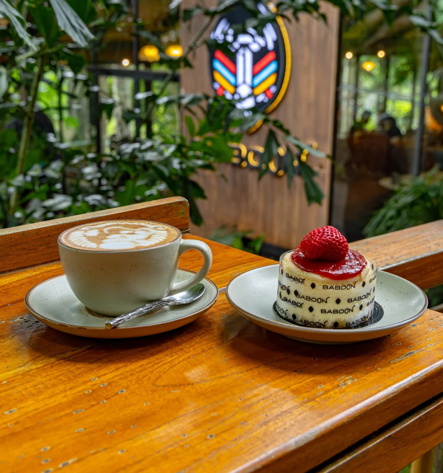 Coffee and a small strawberry-topped cake on a wooden table at Baboon