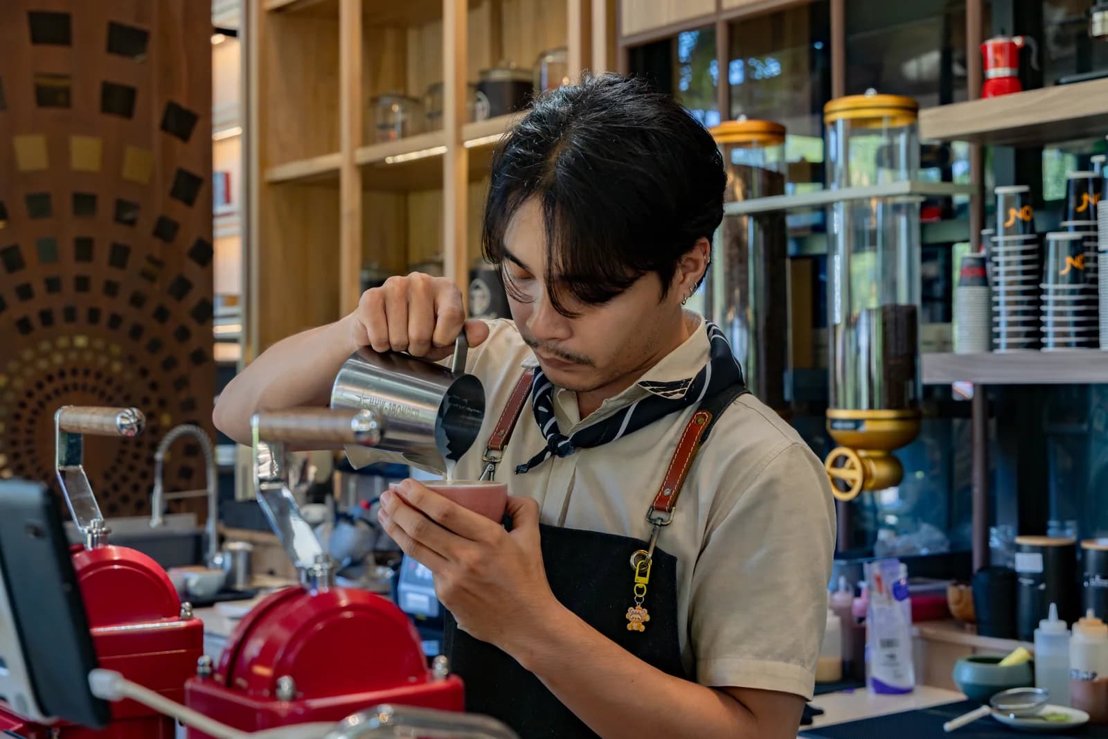 Baboon barista pouring milk into a ceramic coffee cup