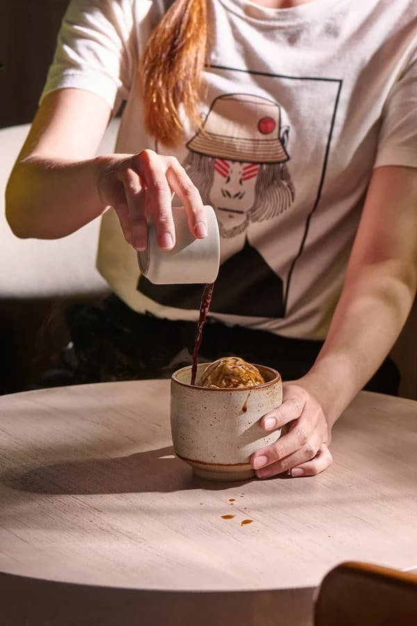 Espresso being poured over ice cream in a ceramic cup