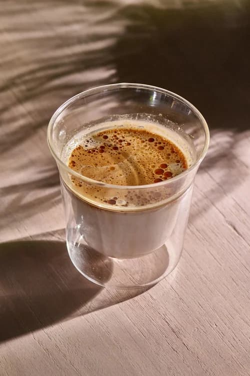 Espresso resting above milk in a small double-walled glass
