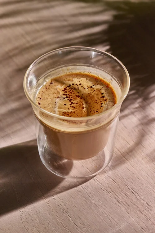 Caramel Dirty coffee in a clear glass on a sunlit table